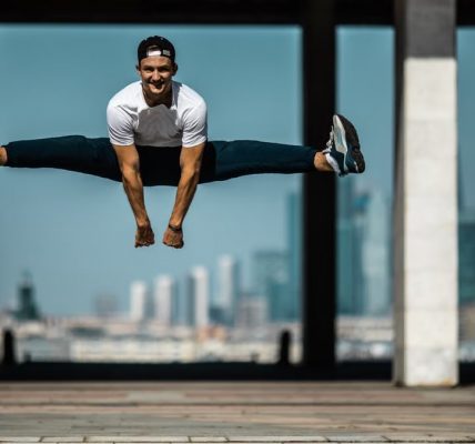 Man performing a split jump on concrete, showcasing fitness and agility.